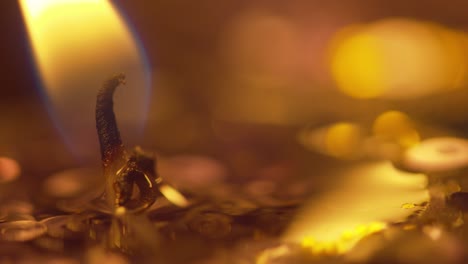 Macro-look-at-the-golden-flame-from-a-candle-and-wick-with-sparkle-and-bokeh-from-the-candles-in-the-background---static