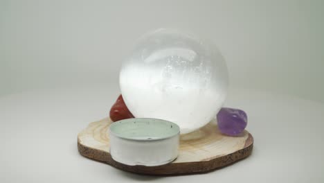 Eine-Spiegelähnliche-Kristallkugel-Sitzt-Auf-Einem-Stück-Holz-Mit-Rotem-Stein-Und-Einem-Kleinen-Kerzenhalter-–-Nahaufnahme