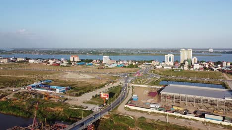 Aerial-static-panoramic-shot-of-traffic-on-road-and-Mekong-river-in-background-on-sunny-day,Cambodia