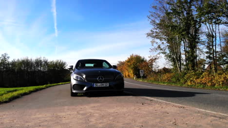 Grey-Mercedes-Benz-C-Class-convertible-car-parked-next-to-rural-road-in-German-countryside,-rotating-left-to-front