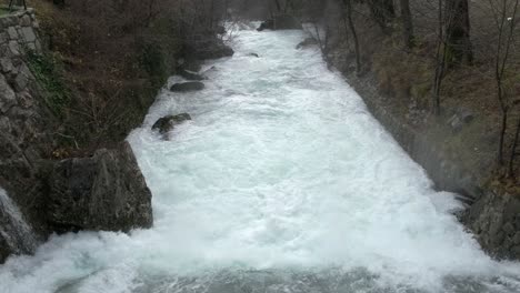 Powerful-white-foamy-water-stream-in-rain,-Tilt-up