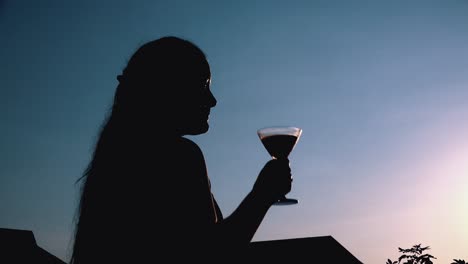 Junge-Frau-Trinkt-Einen-Cocktail,-Der-Sich-Vor-Der-Untergehenden-Sonne-Abhebt