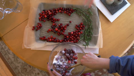 Young-woman-mixing-sugar-and-cranberries-on-wooden-table-for-Christmas-and-holiday-feast-overhead
