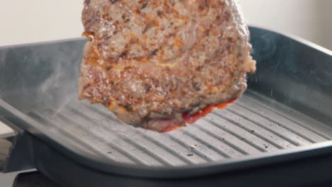 Slow-Motion-Shot-of-Turning-a-Ribeye-Steak-in-a-Cast-Iron-Griddle-Pan