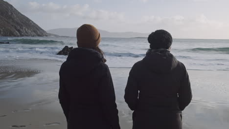 Zwei-Menschen-Beobachten,-Wie-Die-Wellen-Am-Ufer-Der-Achill-Insel-Ankommen