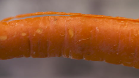 Close-up-of-a-peeler-shaving-the-skin-off-a-carrot