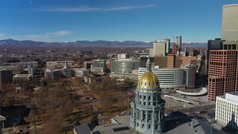 Sideways-aerial-Drone-footage-of-the-Colorado-State-Capitol,-part-of-Downtown,-Capitol-City-park,-civic-center-park,-and-the-McNichols-Civic-Center-Building