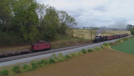 Aerial-View-of-a-Steam-Locomotive-Passenger-Train-Slowly-Pulling-on-a-Siding-with-Smoke-and-Steam