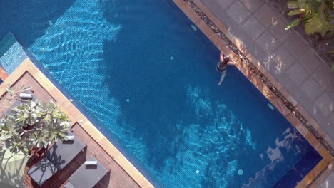 Slow-Drone-Shot-Ascending-and-Rotating-Above-a-Tropical-Hotel-Swimming-Pool