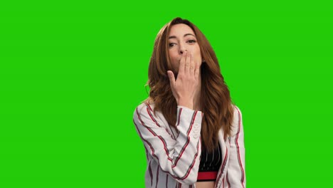 Pretty-young-woman-poses-on-green-screen-showing-heart-gesture-and-blowing-kiss