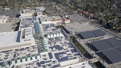 Solar-panels-above-shopping-mall-car-park,-aerial-pan
