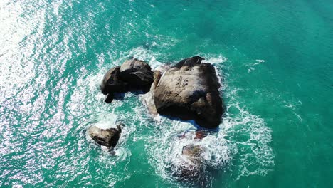 Smaragdglänzendes-Wasser,-Das-Auf-Kalksteinfelsen-Mitten-In-Der-Lagune-Nahe-Der-Küste-Einer-Tropischen-Insel-In-Vietnam-Plätschert-Und-Schäumt