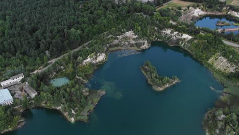 Aerial-View-of-lake-with-Beautiful-Water-in-a-Quarry-Surrounded-by-Forest-and-Small-Town