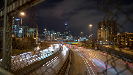 One-second-long-exposure-time-lapse-push-in-revealing-traffic-through-a-hole-in-a-fence-over-the-Kennedy-Expressway-in-Chicago
