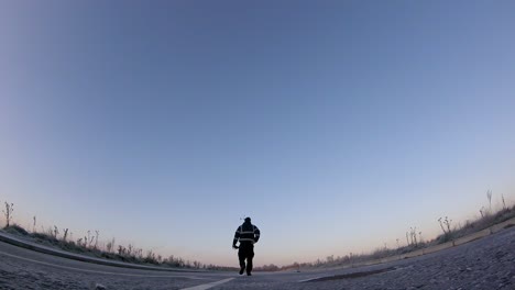 Man-walking-cold-frosty,-long,-empty-road