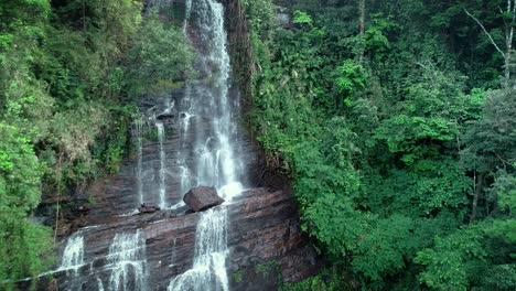 Big-waterfall-on-a-rocky-cliff-amidst-green-tress,-aerial-straight-angle
