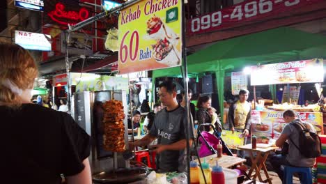 Escenas-De-Mano-De-Los-Turistas-Caminan-Por-La-Calle-Khao-San-En-La-Noche-Famosa-Que-Cada-Año-Turistas-De-Muchos-Países-Venían-A-Visitar-En-Bangkok,-Tailandia