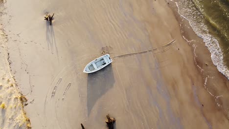 Aerial-view-of-Baltic-sea-coastline-at-Bernati-beach-in-Latvia,-flying-upwards-over-white-sand-beach-and-fisherman-boat,-wide-angle-circular-establishing-drone-shot