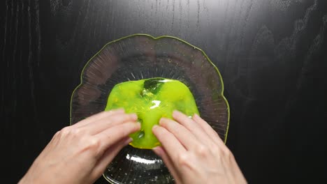 Kneading-a-yellow-slime-with-fingers-in-a-glass-bowl