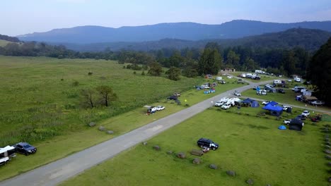 Evacuation-camp-zone-near-the-Warragamba-bushfire-with-vehicles-and-tents-from-mandatory-evacuees,-drone-dolly-out-reveal-shot