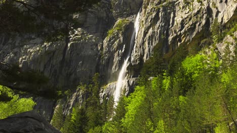 Dramatic-rock-face-with-high-waterfall-above-pine-trees