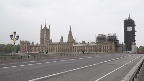 Several-people-walk-pas-the-Houses-of-Parliament-as-they-cross-a-deserted-Westminster-Bridge-during-the-Coronavirus-outbreak