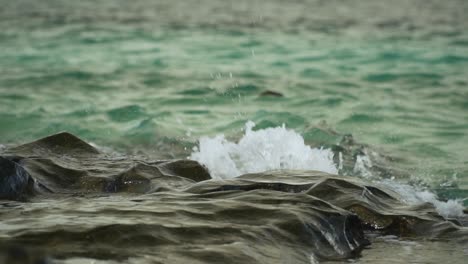 Splash-of-ocean-water-on-rocks-creating-beautiful-patterns,-slow-motion