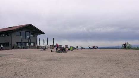 People-relax-on-plateau-next-to-a-restaurant-on-cloudy-day,-Hornisgrinde,-Germany