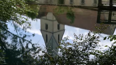 Reflexion-Eines-Kirchturms-Im-Kristallklaren-Wasser-Des-Blautopfsees-In-Blaubeuren,-Schwäbische-Alb,-Deutschland