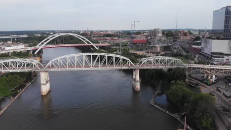 White-truss-bridges-above-narrow-river-by-downtown-Nashville-city,-Illinois,-aerial-approach