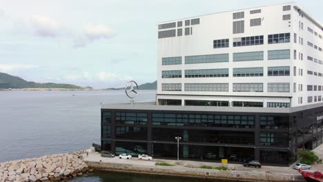 Large-Mercedes-Benz-sign-spinning-on-top-of-Hong-Kong-Mercedes-Benz-main-showroom-in-Chai-Wan-area,-Aerial-view
