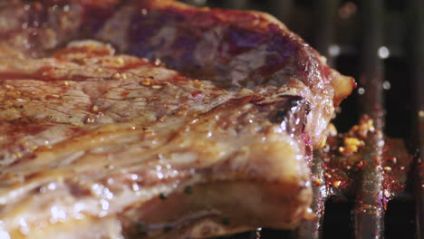 Close-up-of-a-juicy-ribeye-steak-cooking-on-a-grill
