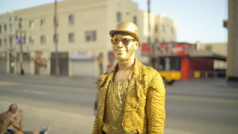 Einsamer,-In-Gold-Gemalter-Straßenkünstler,-Der-An-Einem-Sonnigen-Tag-Während-Des-Coronavirus-Ausbruchs-Auf-Dem-Hollywood-Boulevard-Steht-Und-In-Die-Kamera-Lächelt