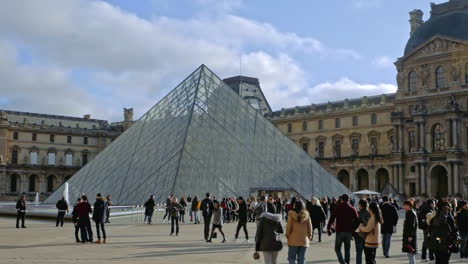 Dolly-Right-Shot-Louvre-Museum-Pyramid-Square-with-Tourists-Walking
