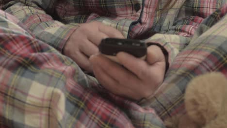 Woman-in-pajamas-using-mobile-phone-close-up