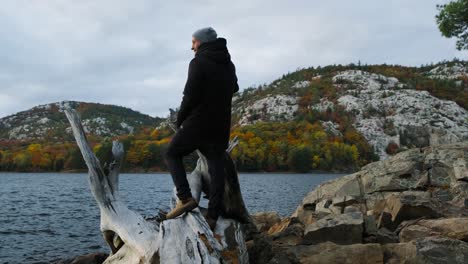 Climbing-a-Log-in-Fall-Tree-Colours-in-Slow-Motion,-Wide-Handheld-Pan