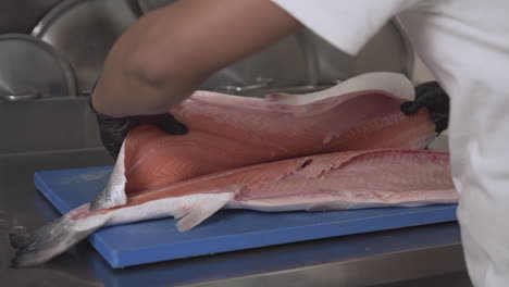 Close-Up-Shot-of-a-Chef-Filleting-and-Flipping-over-a-Fresh-Salmon-Fish