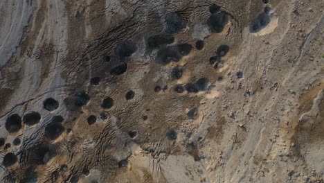 Aerial-top-down-shot,-zooming-out-of-many-small-sinkholes-in-the-desert,-Israel