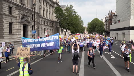 Hundreds-of-National-Health-Service-staff-and-key-workers-march-past-the-Cenotaph-with-a-large-blue-banner-that-says,-“End-NHS-Pay-Inequality