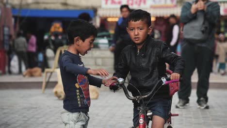 Dos-Niños-Andando-En-Bicicleta-Y-Jugando-En-El-Mercado-Callejero-Del-Leh