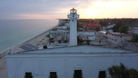 Low-aerial-push-in-at-sunrise-towards-the-lighthouse-in-Telchac-Puerto-in-Yucatan,-Mexico