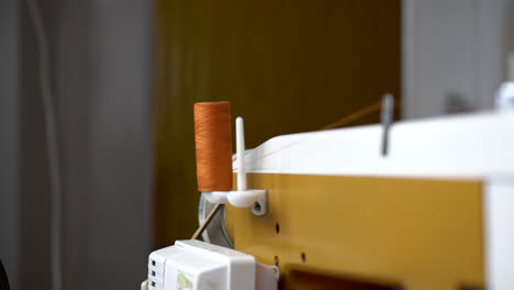 White-sewing-machine-taking-orange-thread-from-the-reel