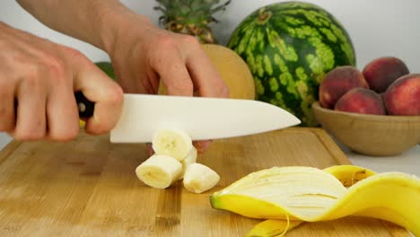 Cortar-Un-Plátano-En-Una-Tabla-De-Cortar-De-Bambú,-Usando-Un-Cuchillo-De-Cerámica