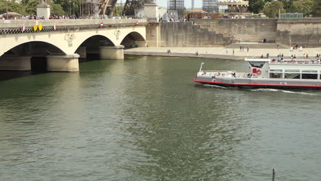 Ausflugsboot-Auf-Der-Seine-Mit-Touristen,-Die-Unter-Der-Iena-Brücke-Vor-Dem-Eiffelturm-Hindurchfahren