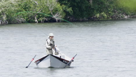 Two-men-fly-fishing-in-Idaho's-Snake-river-on-boat,-zoom-in-shot