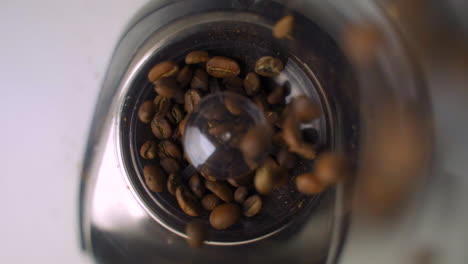 Slow-motion-up-close-overhead-view-of-fresh,-brown-coffee-beans-being-poured-into-fancy-electric-grinder-for-morning-coffee