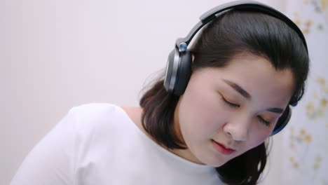 Close-up-Asian-beautiful-woman-using-the-bluetooth-headphone-for-listening-to-music-so-lovely-lie-in-bed