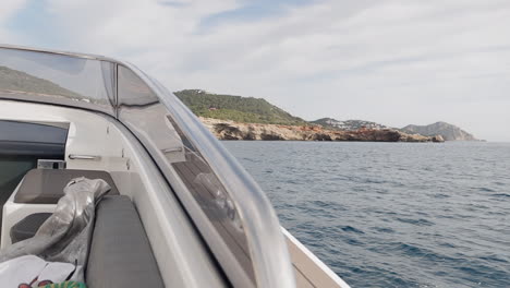Traveling-from-the-bow-of-a-luxury-boat,-and-the-backgroud-the-coast-of-Ibiza,-Spain
