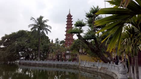 Buddhist-temple-Tran-Quoc-pagoda-from-the-sixth-century-with-lake-and-tourists,-Stable-handheld-shot