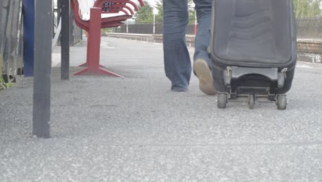 Commuter-wheels-suitcase-on-train-platform-wide-shot